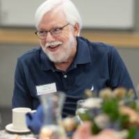Terry Allen smiling while listening to someone at his table